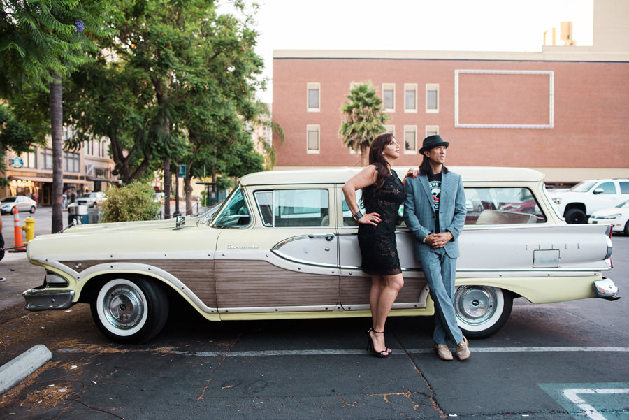 A couple pose in front of a classic car in downtown san jose