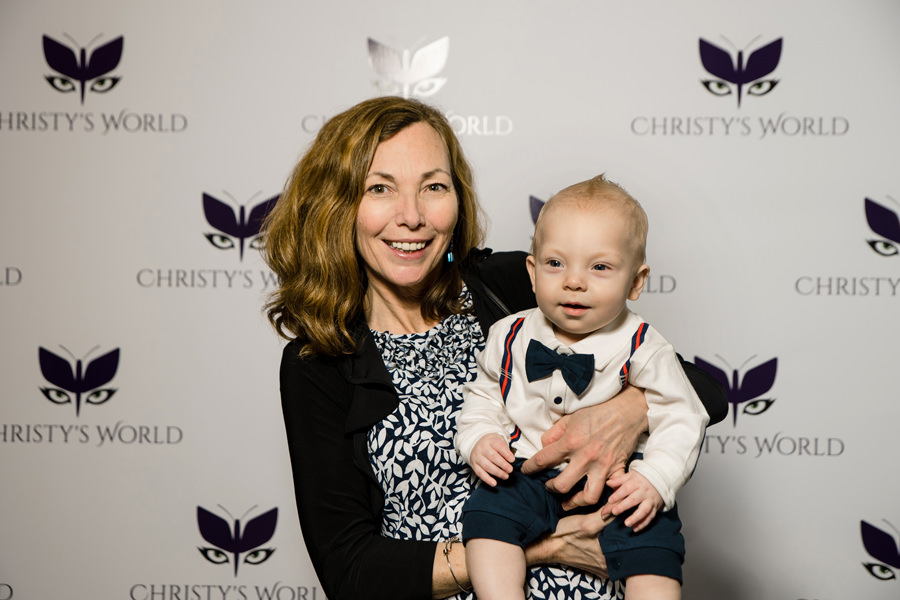  Step and repeat photo of a lady with a cute baby in front of a custom background photo taken at a Birthday Party at Hotel Valencia 