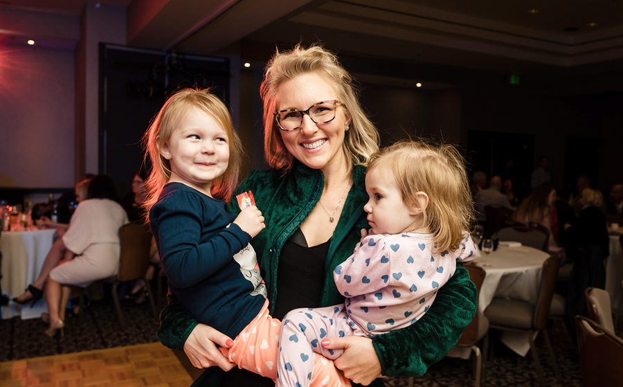A cute picture of a toddler danced with her mother at a party.