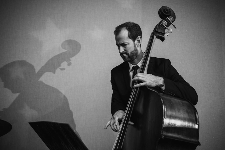 Great black and white image of a bassist with his shadow on the wall.
