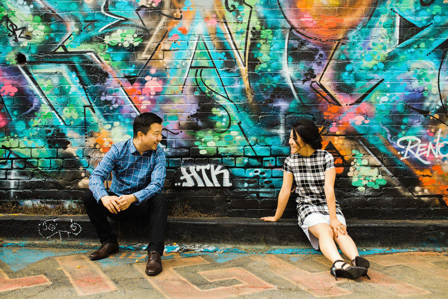 A couple sits on the sidewalk as a part of SF Fun Engagement Session