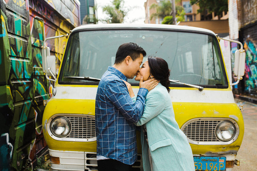 A couple kisses for a photo in front of a classic car