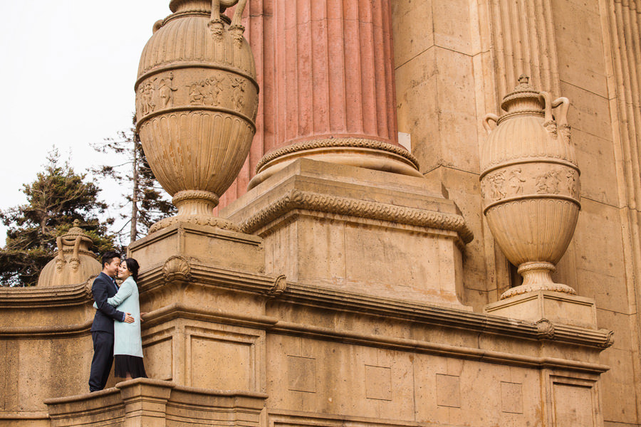 A cute couple posing on top of the Palace of Fine Art's structure