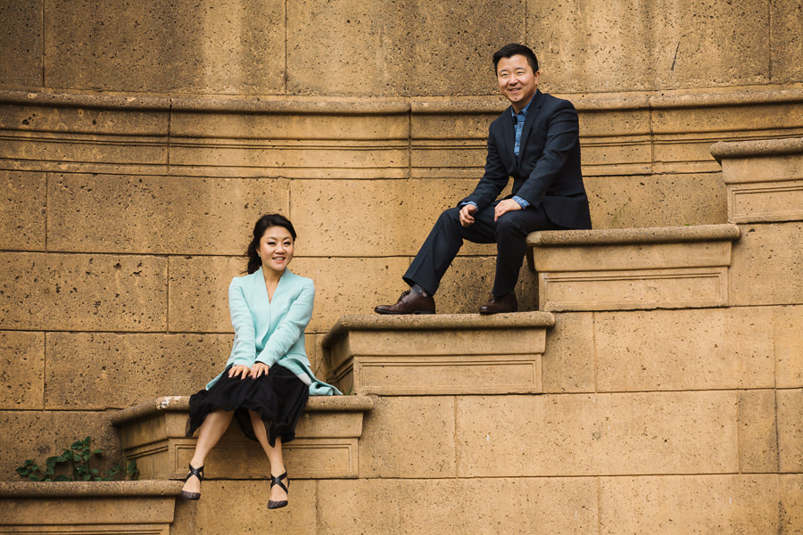An engaged couple sits and pose at the Palace Of Fine Art SF