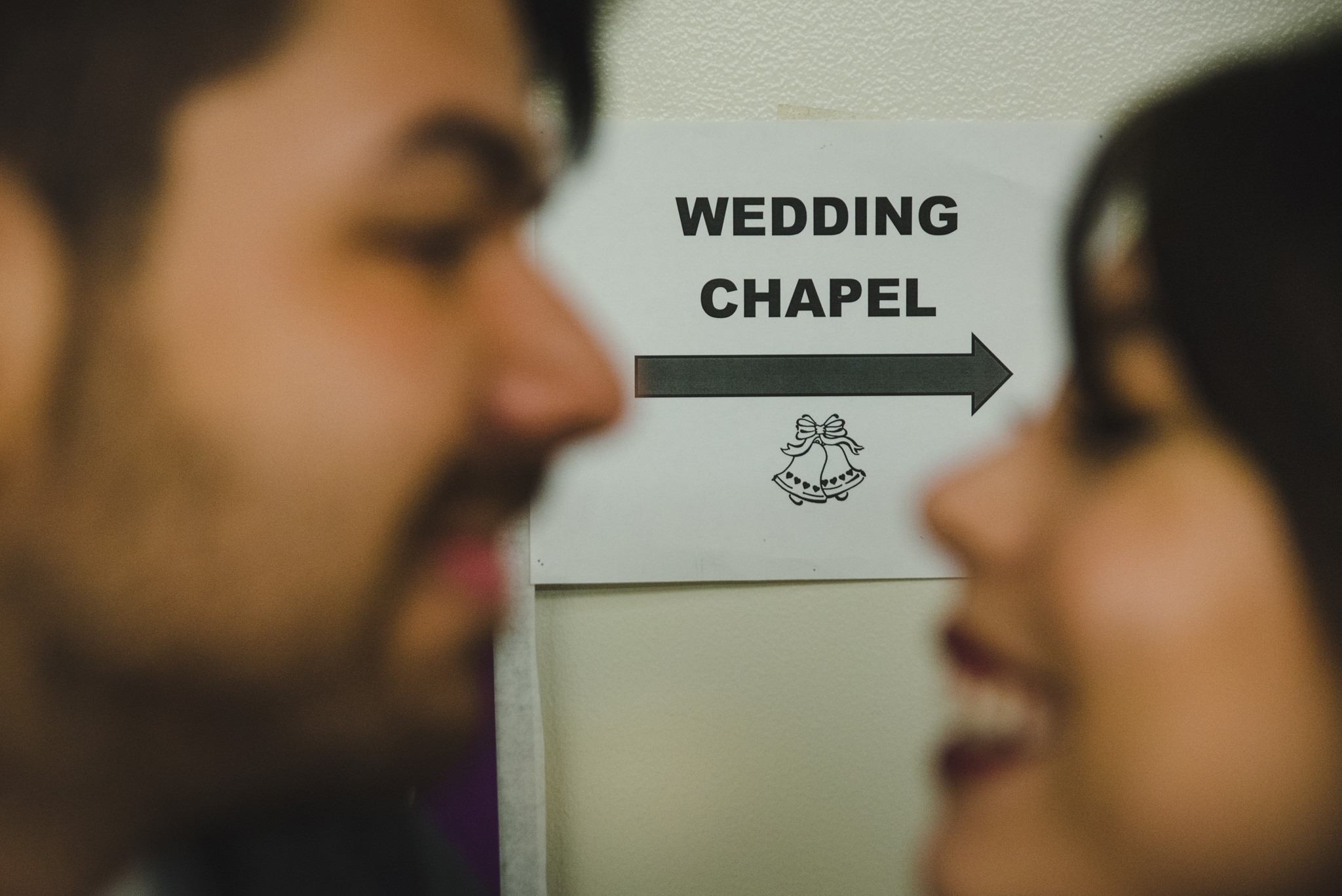 A Wedding couple glanced at each other in front of the Chapel's sign at the San Jose Clerk Recording Office