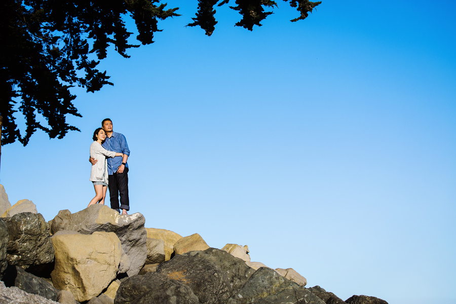 A couple standing on rock on the beach overlook to the sea