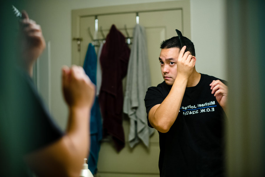 A groom combing his hair in front of a mirror getting ready for his wedding at casa bella in Sunol