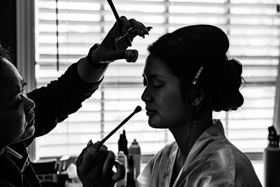 a black and white photo of a bride getting her make up done