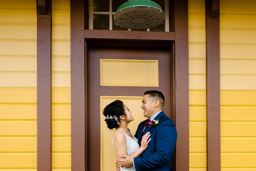 An image of a newly wed smiling to each other in front of a door