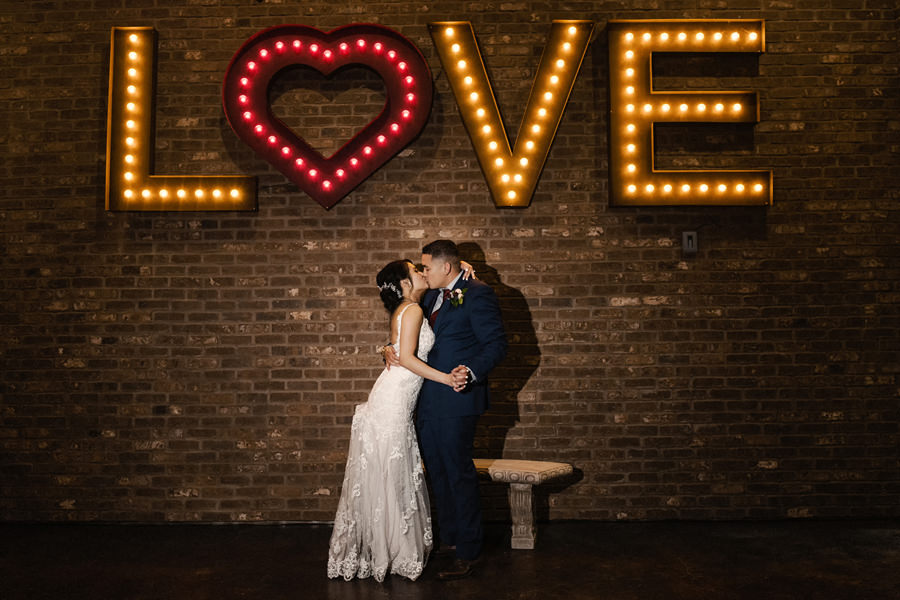 A cool image of a newlywed under the neon sign that says Love