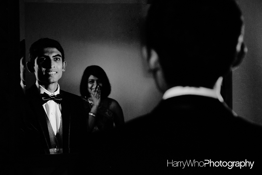 Cool Wedding Photo in black and white of a groom while his wife giggling in the back
