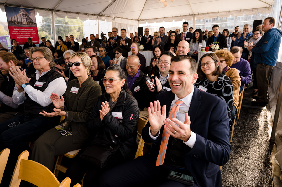 Crowd of guests clapping at a ground breaking ceremony.