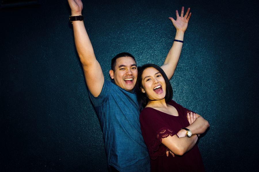 An image of a couple having fun in front of a blue wall