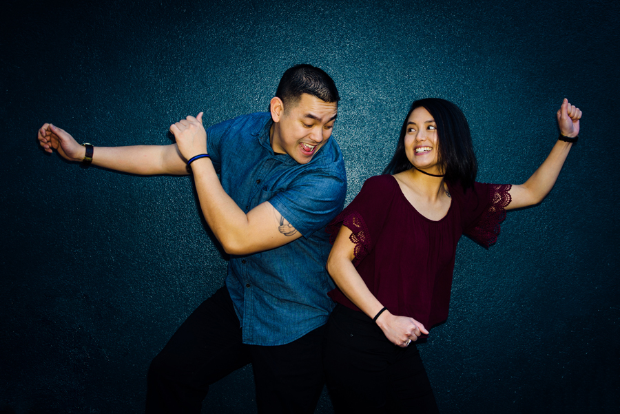 An image of a couple having fun in front of a blue wall