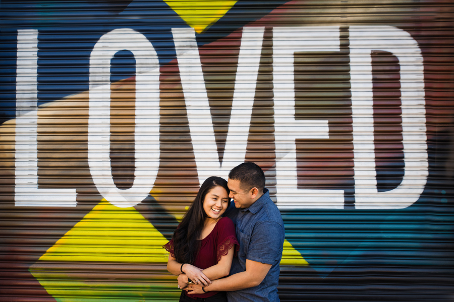 A great image of a couple embraced in front of painted garage door with the word LOVED