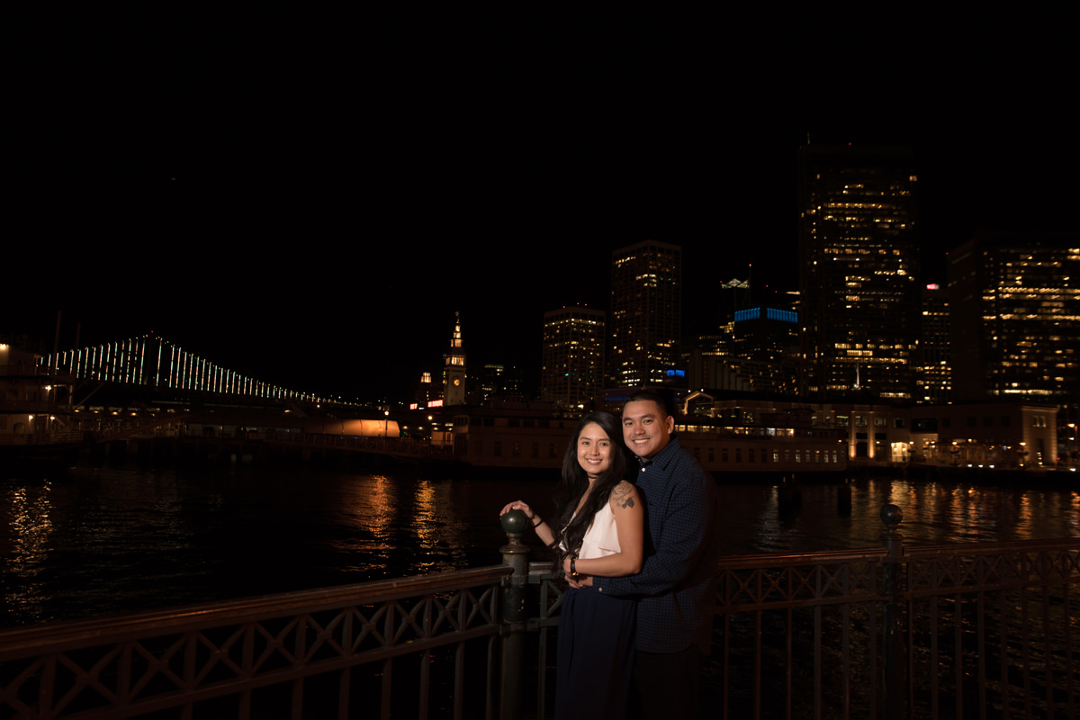 An image of an engaged couple with SF's City lights in the background