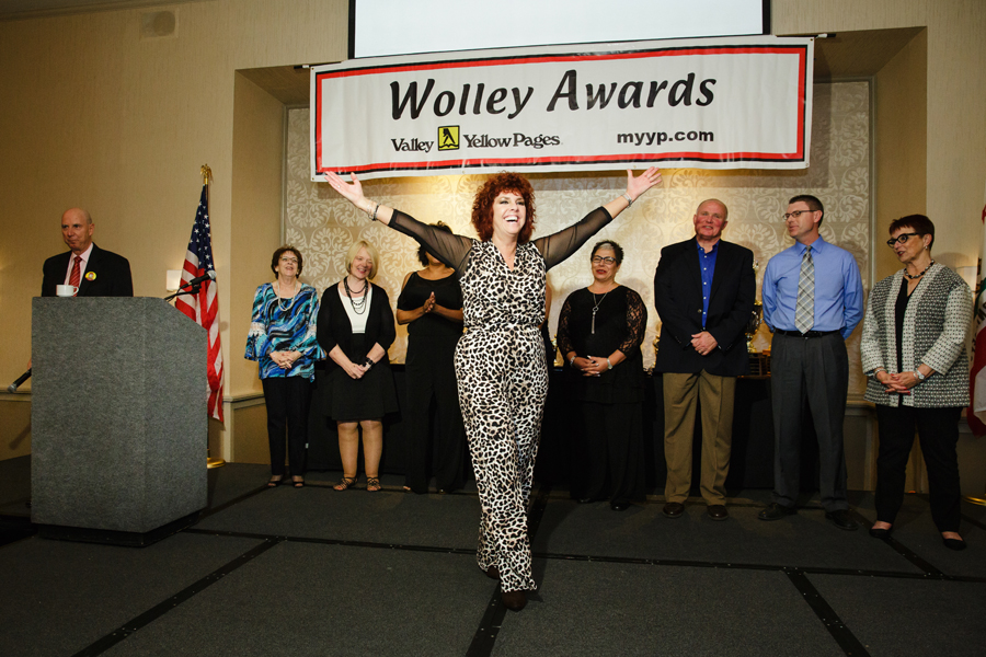 An award recipient being elated by opening her arms on the stage