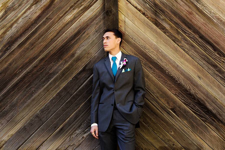 A groom pose for his portrait on a chevron pattern wooden wall