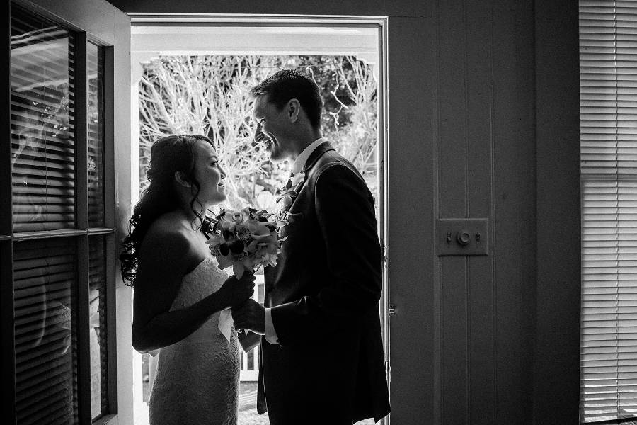 A couple smiles at each other while standing at the door
