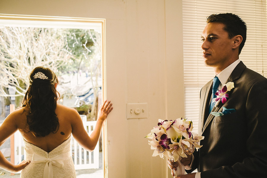 Artistic image of a wedding couple with the groom holding the bouquet and bride looking away outside the door