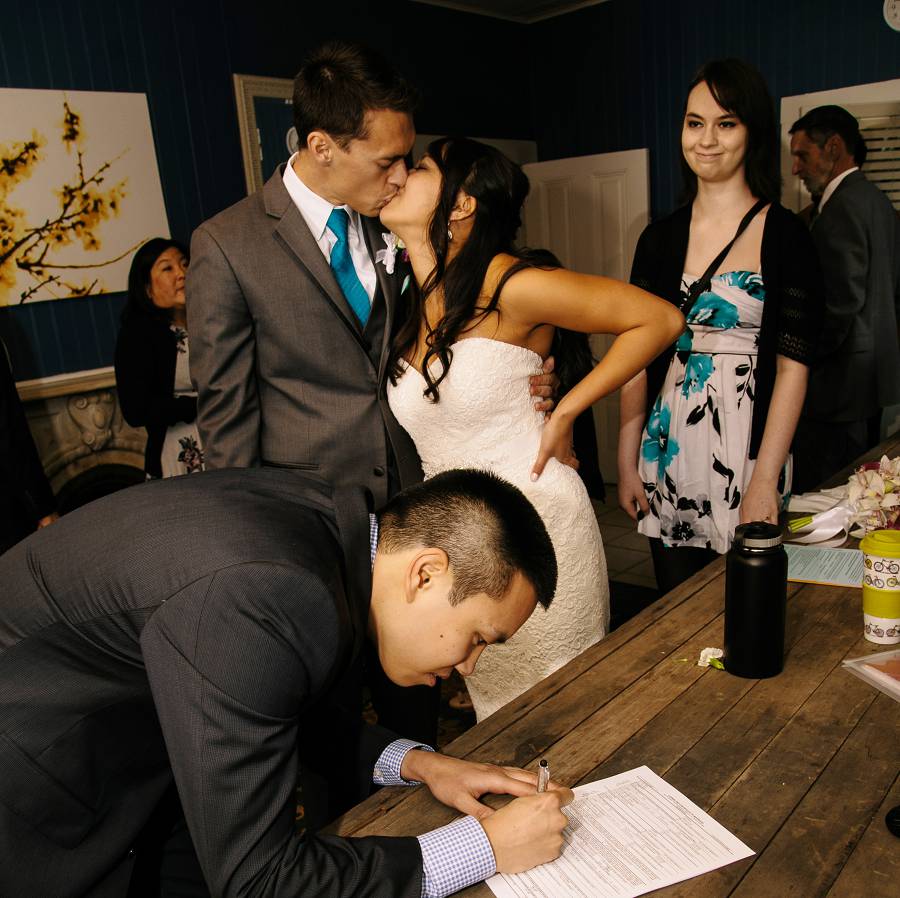 Bride and Groom kissed while the Witness sign the Wedding license