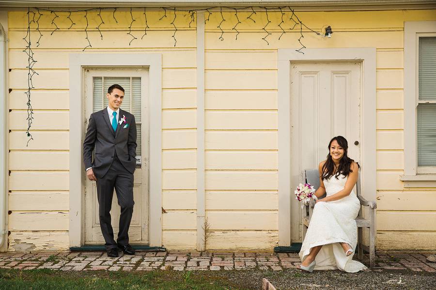 Groom standing and bride sitting in front of doors for a portrait