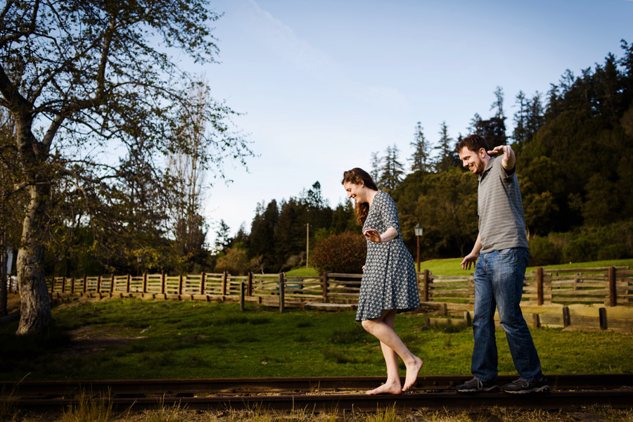 A candid moment as a couple walking and balancing on the rail track.