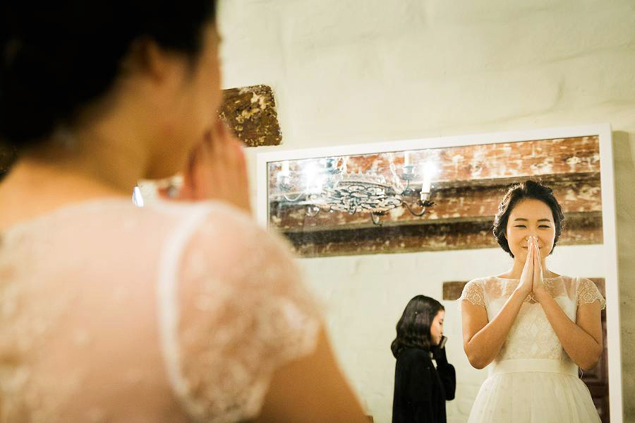 A bride happy to see how she look sin the mirror on her wedding day
