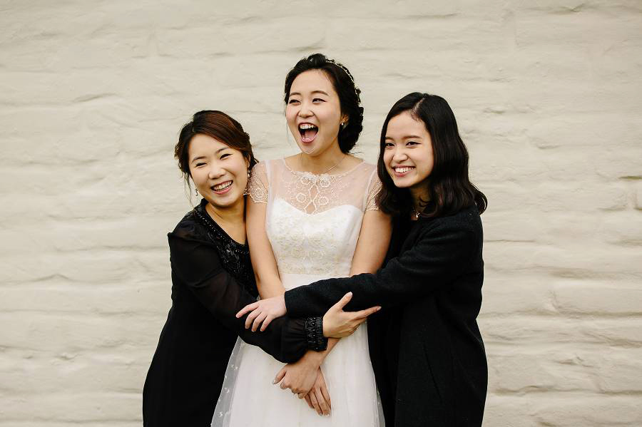 A bride hugged by her best friend and her sister 