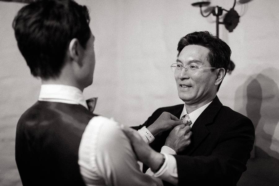 Groom and his father help each other in straightening their ties
