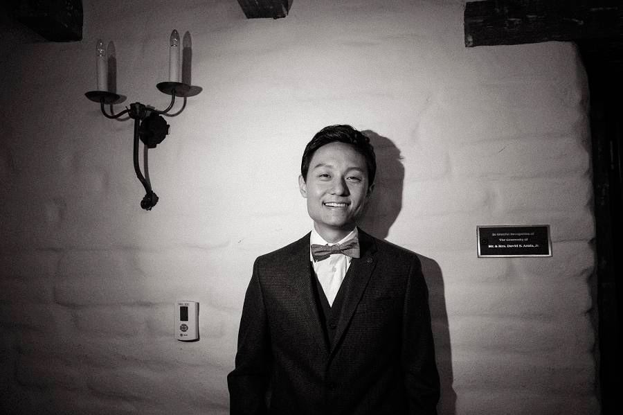 A groom poses for the camera after he puts on his bowtie