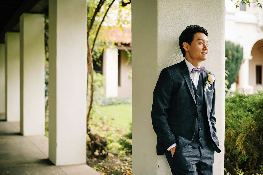 A groom standing next to a pillar before his Santa Clara University Mission Church Wedding