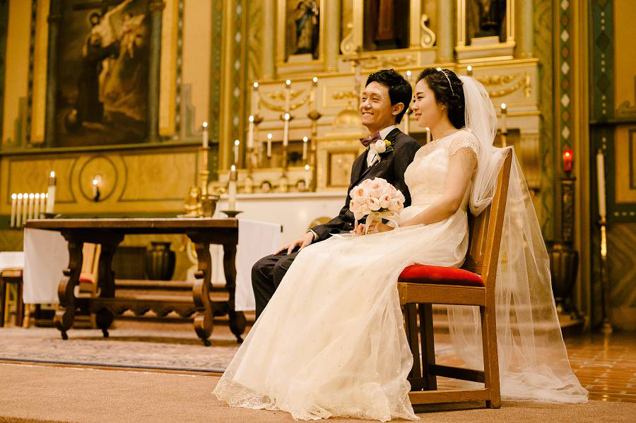 Bride and Groom sitting at the altar of Santa Clara University Mission Church
