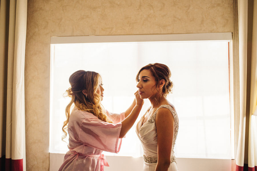A maid of honor helping to put on the bride's earrings