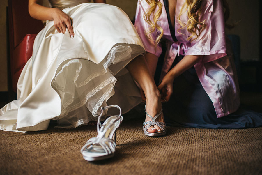 A bride putting her shoes helped by her maid of honor