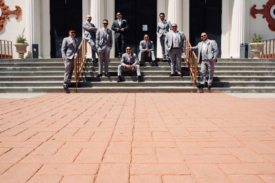 The groom and groomsmen pose in front of the church
