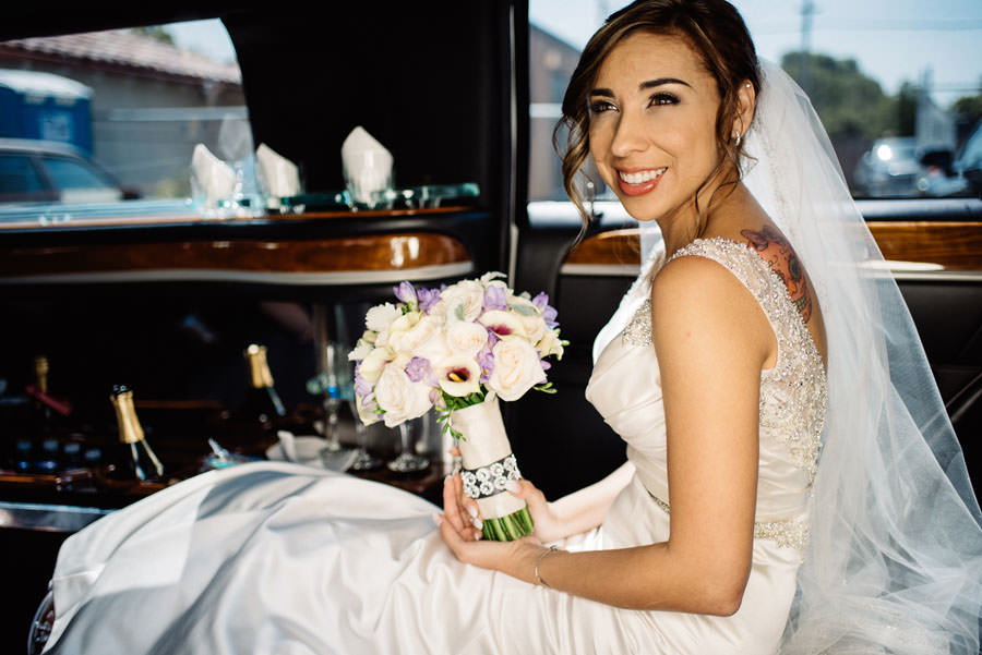 A bride smiles as she waits in her limo