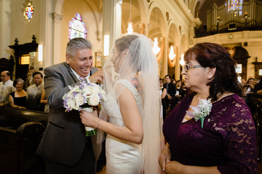 An elated father lifts up his daughter's wedding veil