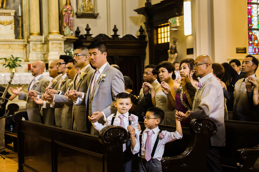 Groomsmen and ring bearers holding hands during the Catholic ceremony