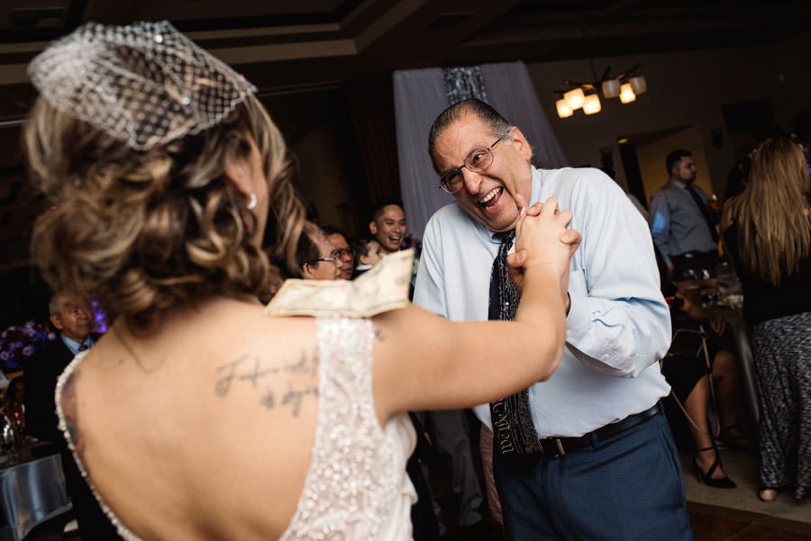 A man laughs at the bride while dancing with her