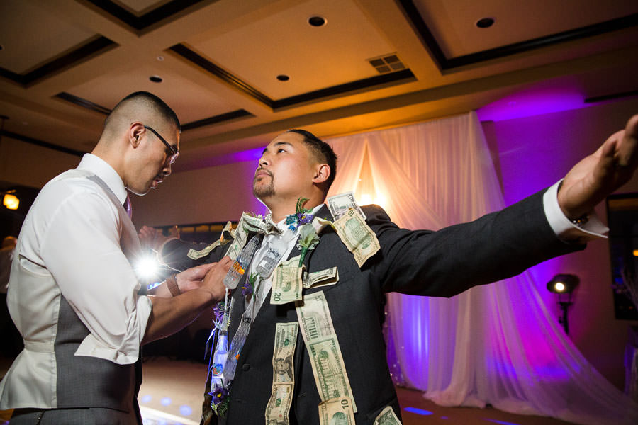 Groomsmen pinning his money on the groom's sleeve