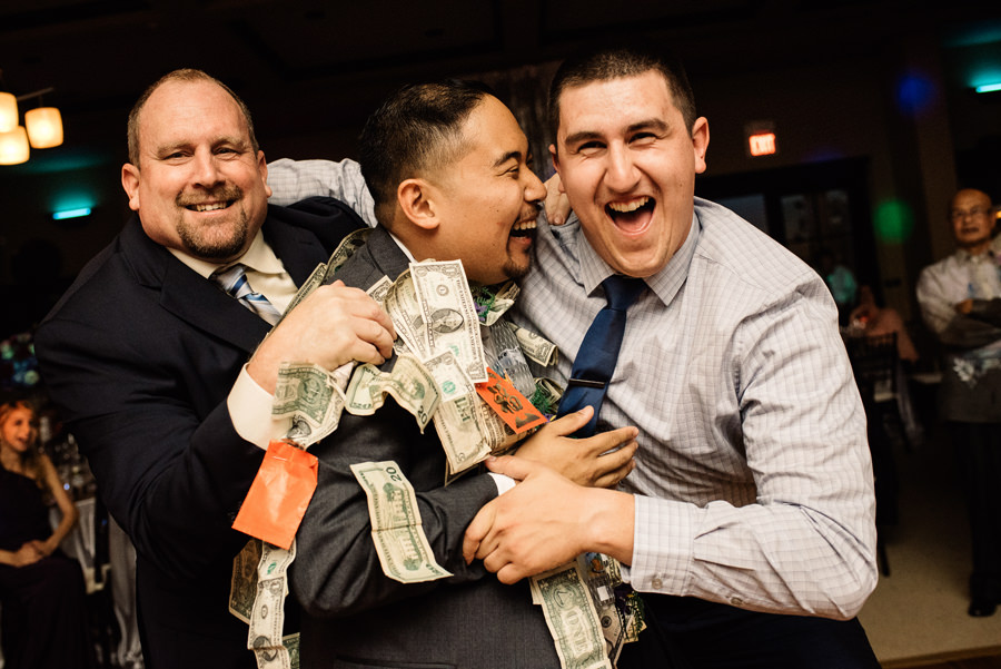 Two Guests hug the grooms during the money dance