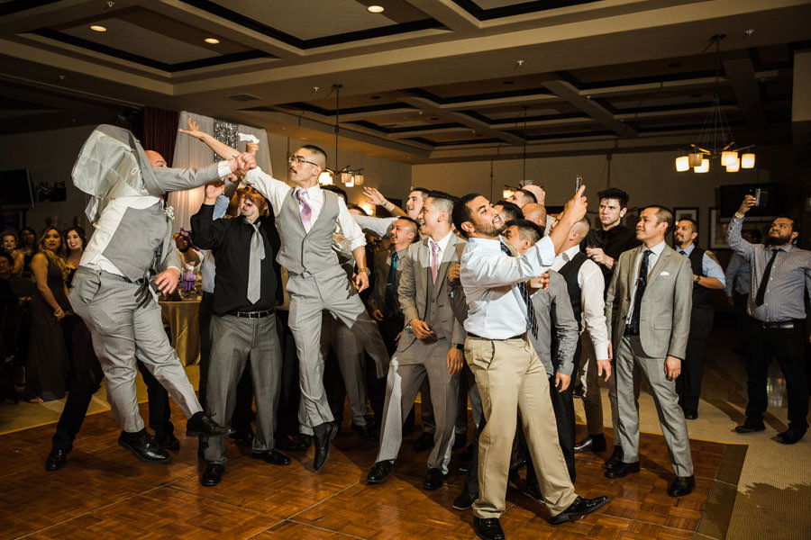 A group of guys trying to catch the garter on the flight